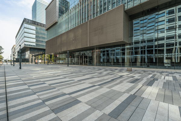 an empty sidewalk in front of a large building .