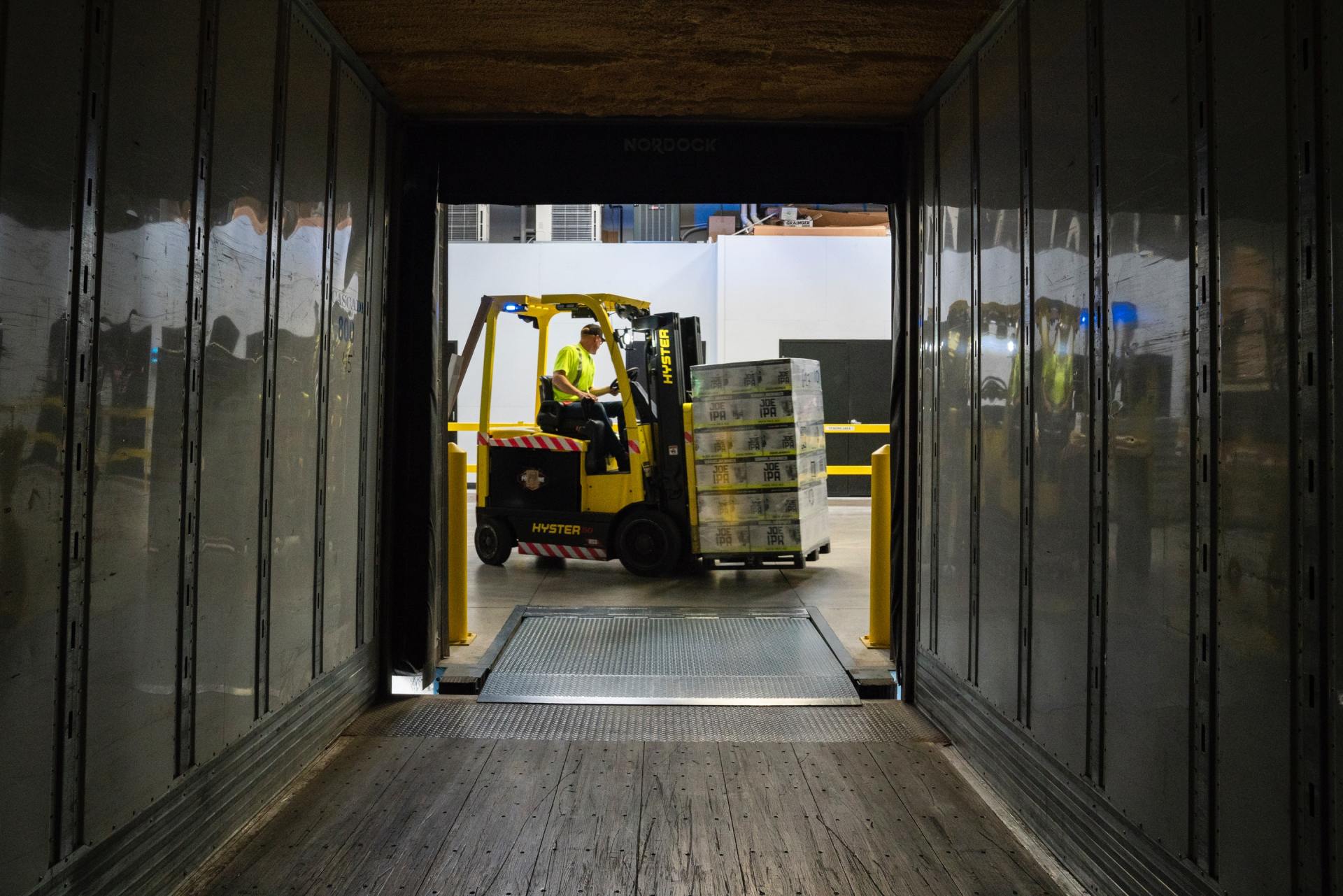 a forklift is loading boxes into a truck in a warehouse .