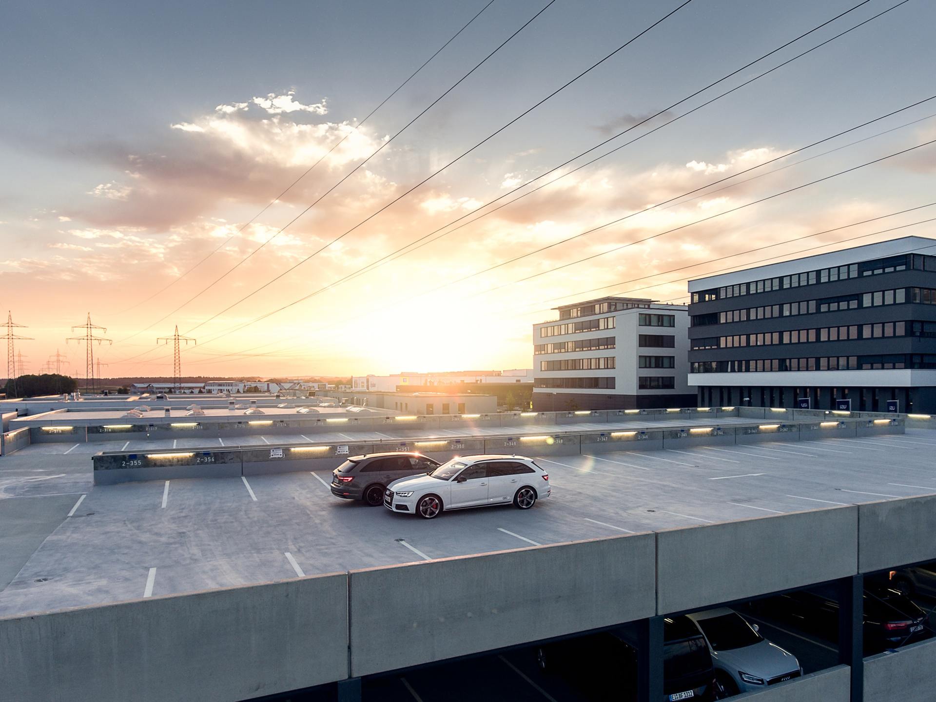 a parking garage with cars parked on the roof at sunset .
