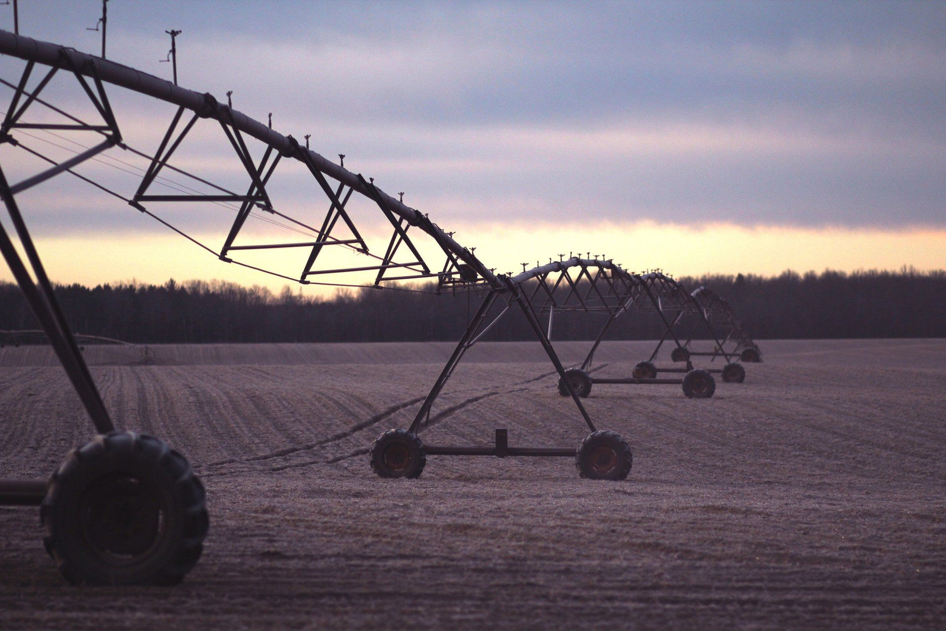 a row of irrigation equipment in a field at sunset