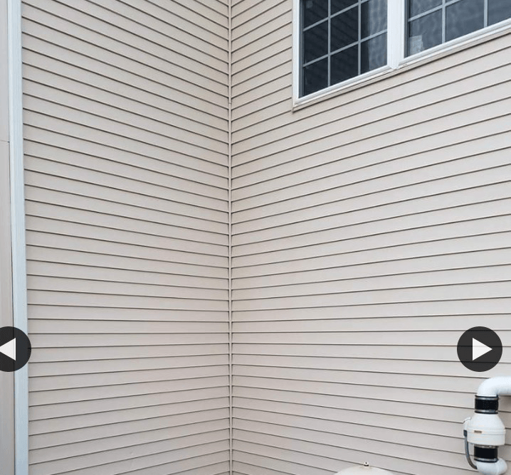 Beige siding corner of a building with a window and white trim.