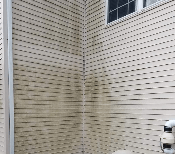 a corner of a house with a dirty siding and a window .