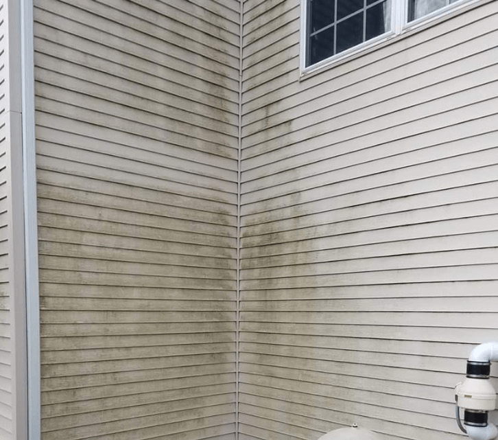 Dirty beige vinyl siding on a house corner, with dark streaks of dirt.