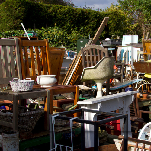 Pile of assorted furniture and objects outdoors; brown, white, and green dominate.