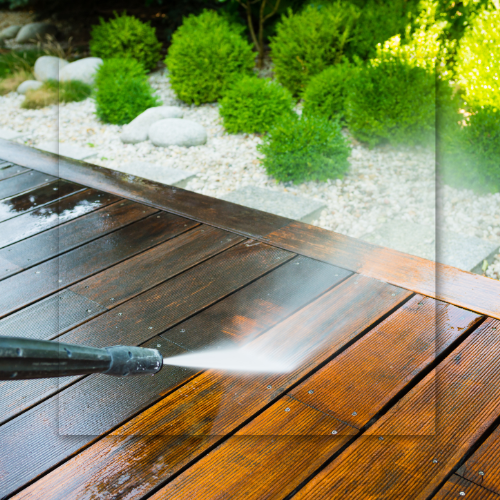 Pressure washing a wooden deck; spray removes dirt, revealing the clean wood.