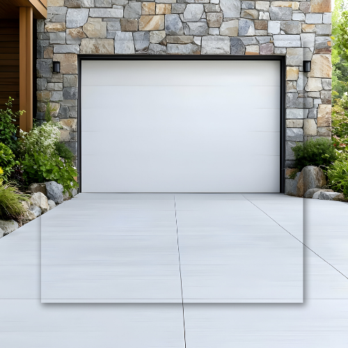 White garage door framed in black set into stone wall, with concrete driveway.