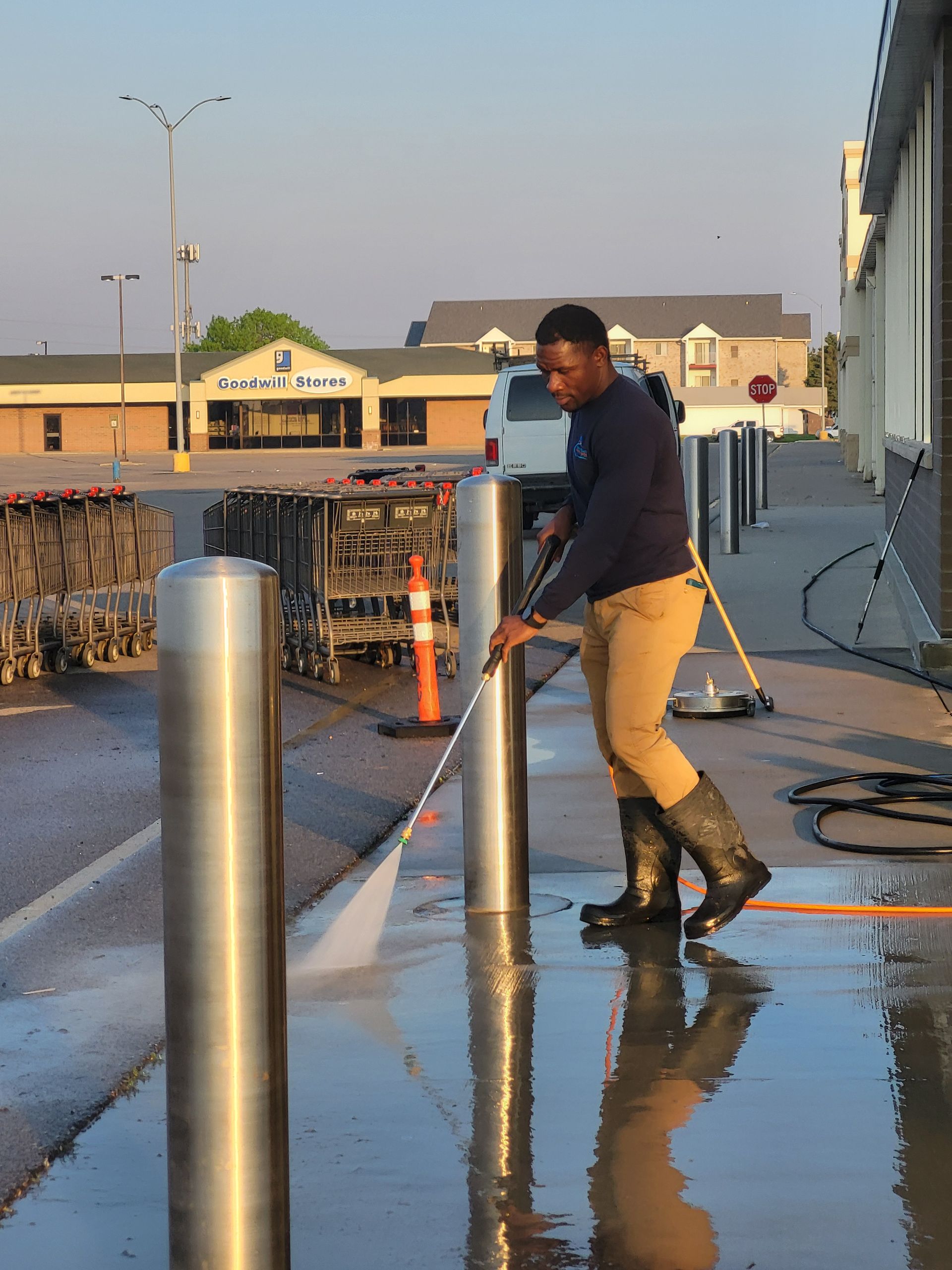 A man is using a high pressure washer to clean a sidewalk.