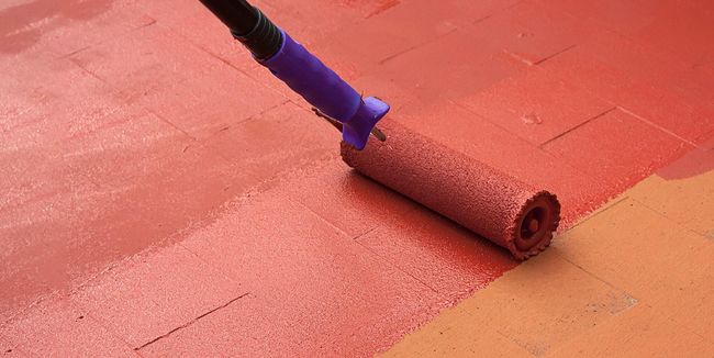 Una persona está pintando un piso de ladrillo con un rodillo.