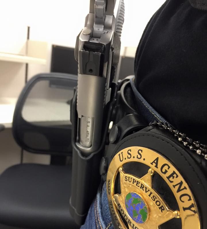 Close-up of a holstered handgun on a police officer's belt.