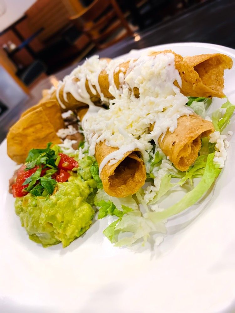 A close up of a plate of food with tacos and guacamole
