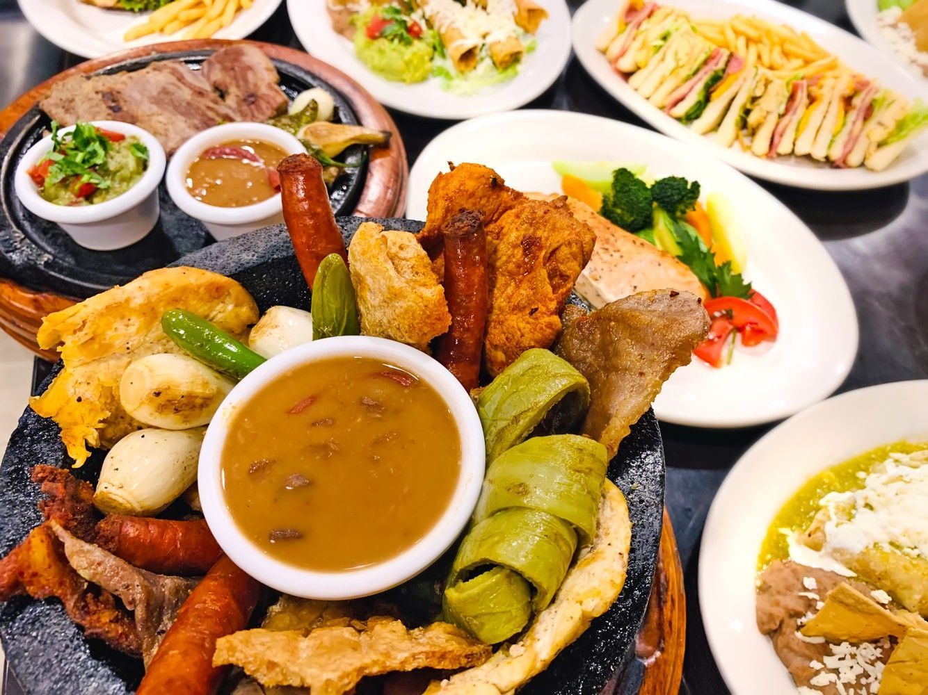 A table topped with plates of food and a bowl of sauce.