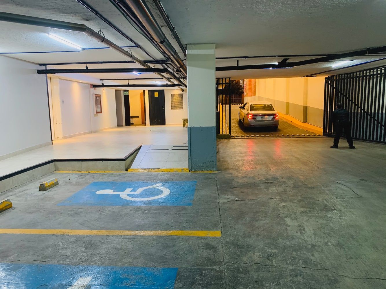 A car is parked in a handicapped parking spot in a parking garage.