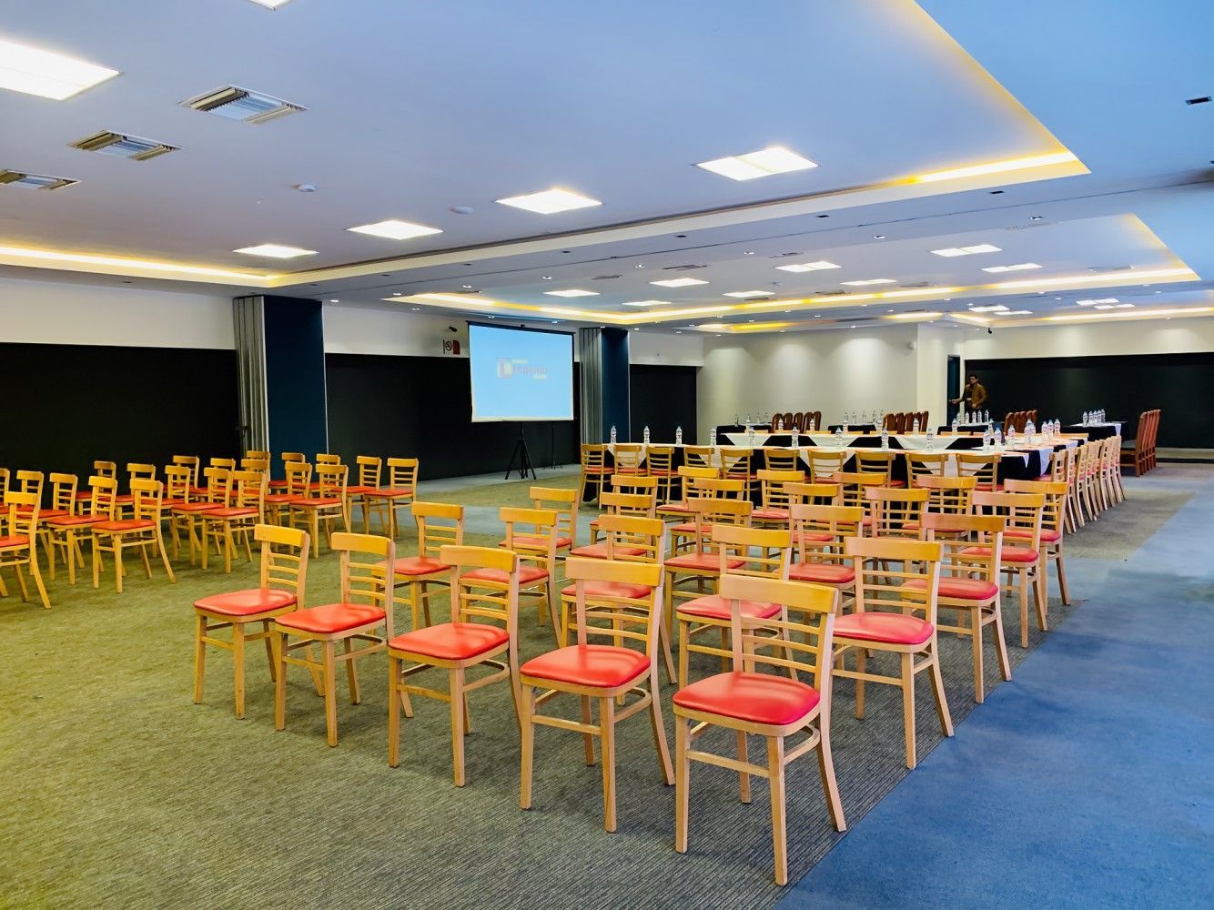 A large room with rows of chairs and a projector screen.