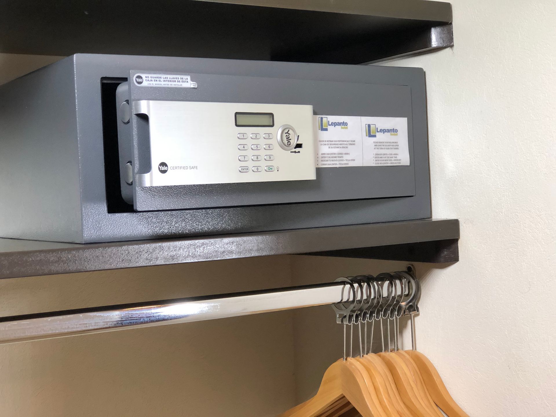 A safe is sitting on a shelf next to a row of clothes hangers
