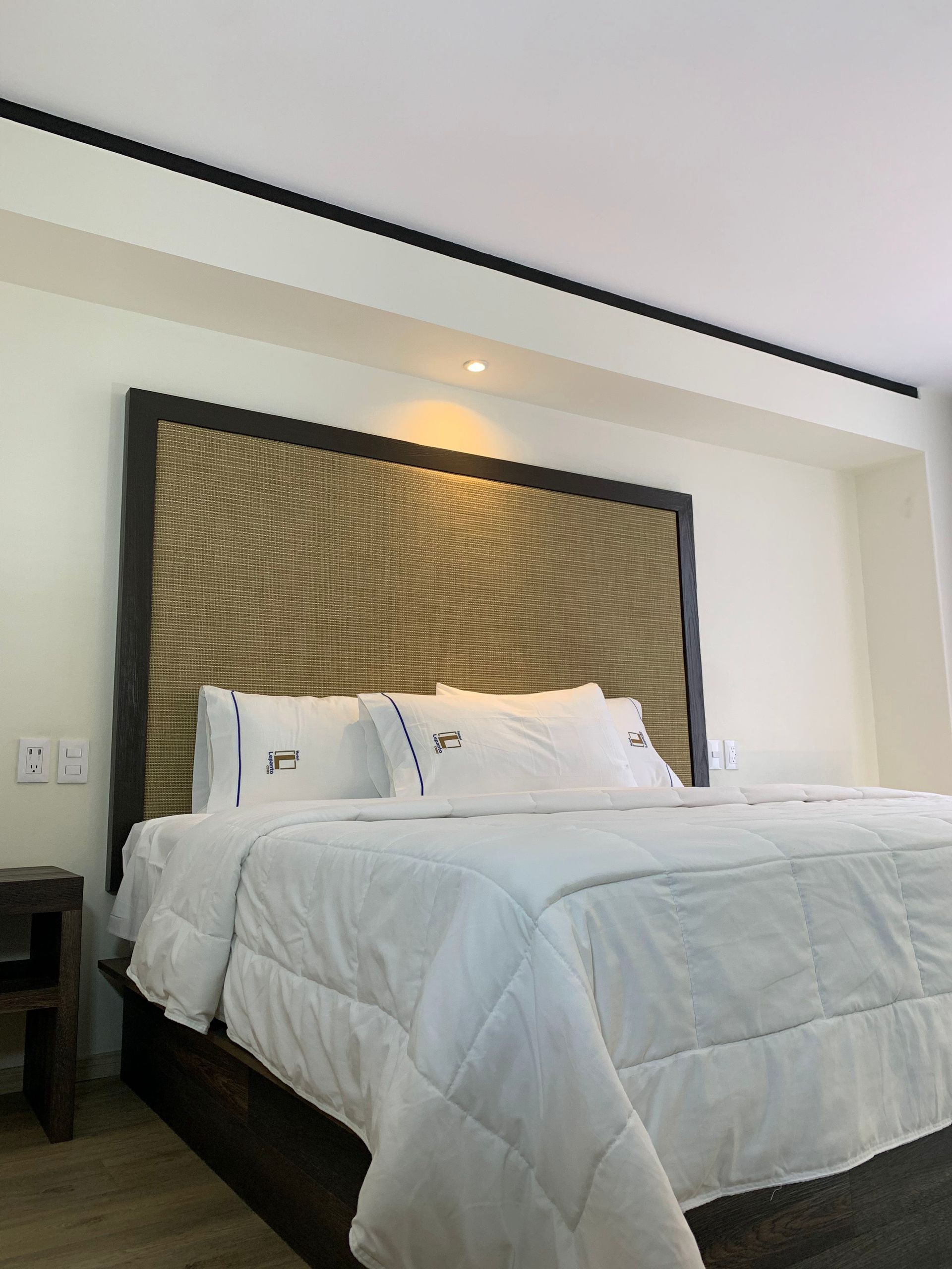 A bed with white sheets and pillows in a hotel room