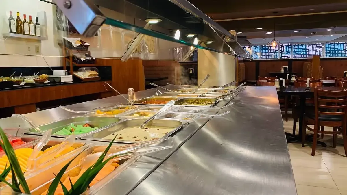 A buffet line in a restaurant filled with lots of food.