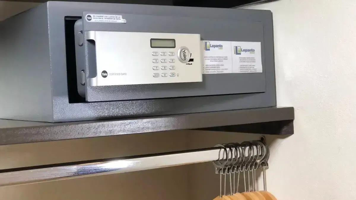 A safe is sitting on top of a shelf next to a hanger.