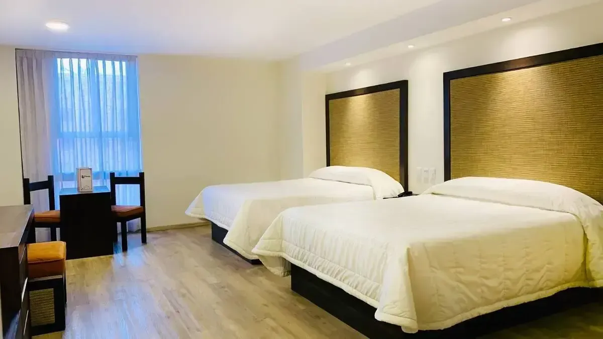 A hotel room with two beds , a table and chairs.