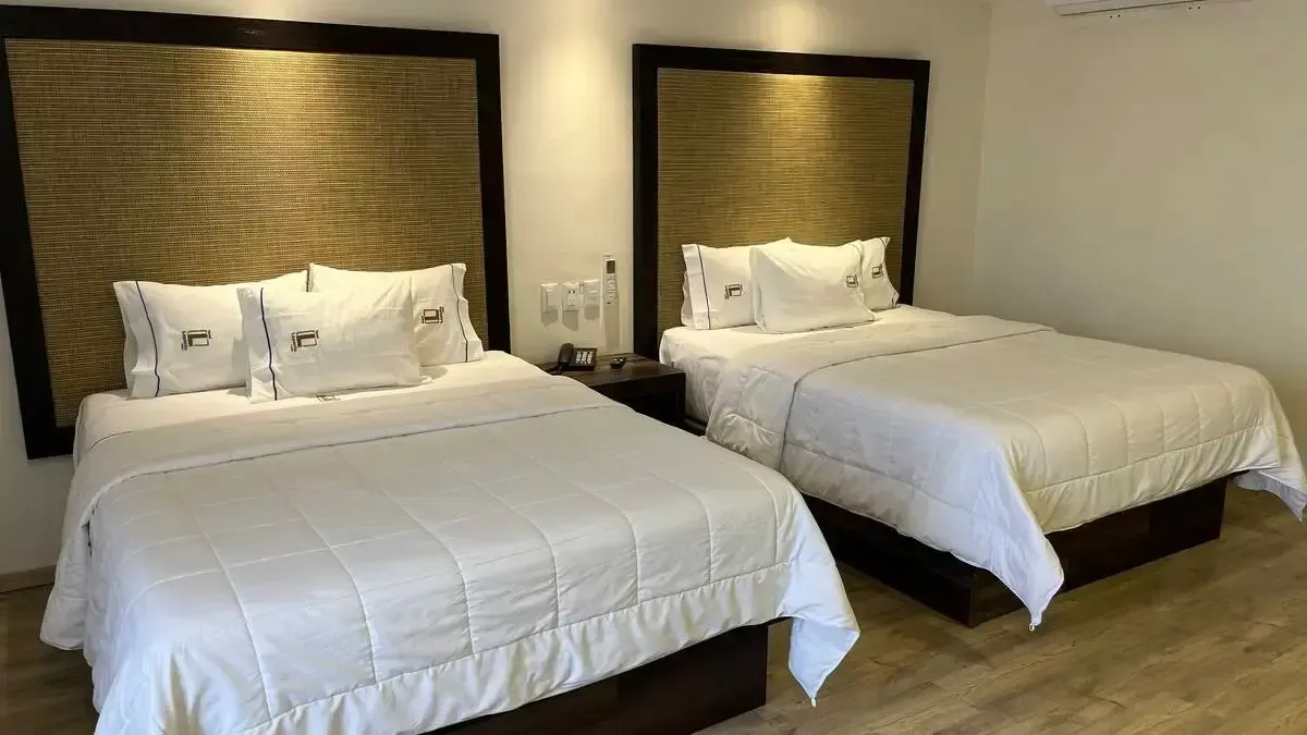 A hotel room with two beds and a wooden floor.