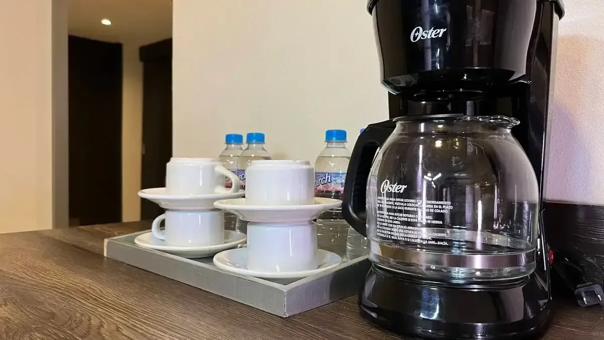 A coffee maker is sitting on a counter next to a tray of cups and saucers.