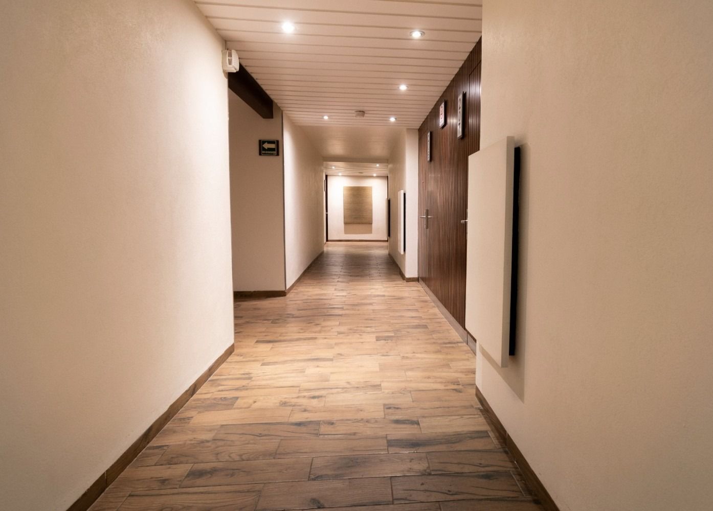 A long hallway with wooden floors and white walls