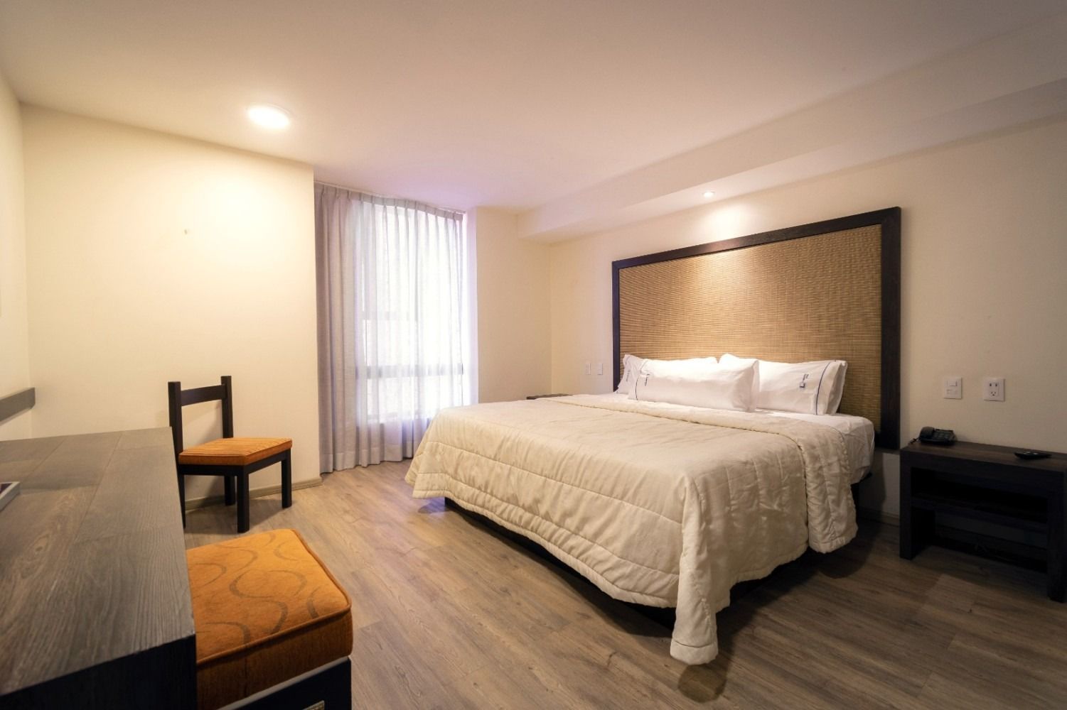 A hotel room with a king size bed and a chair.