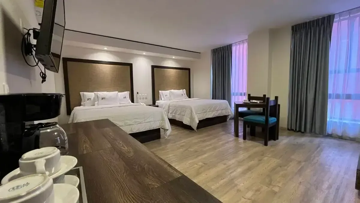 A hotel room with two beds , a table and chairs.