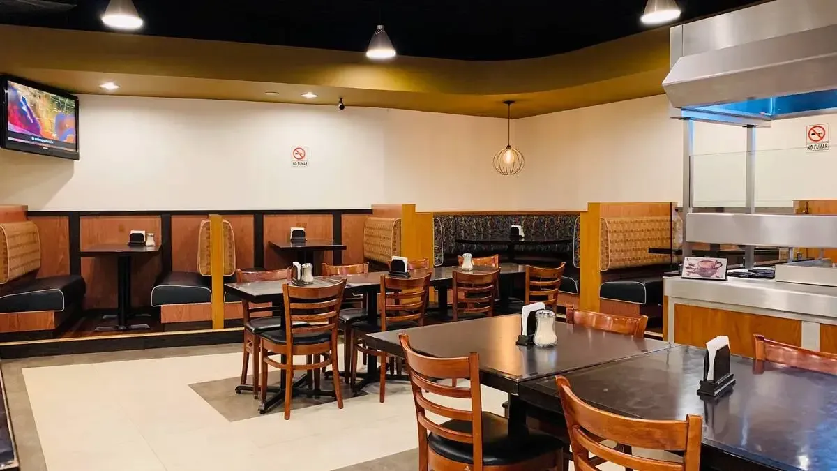 A restaurant with tables and chairs and a television on the wall.