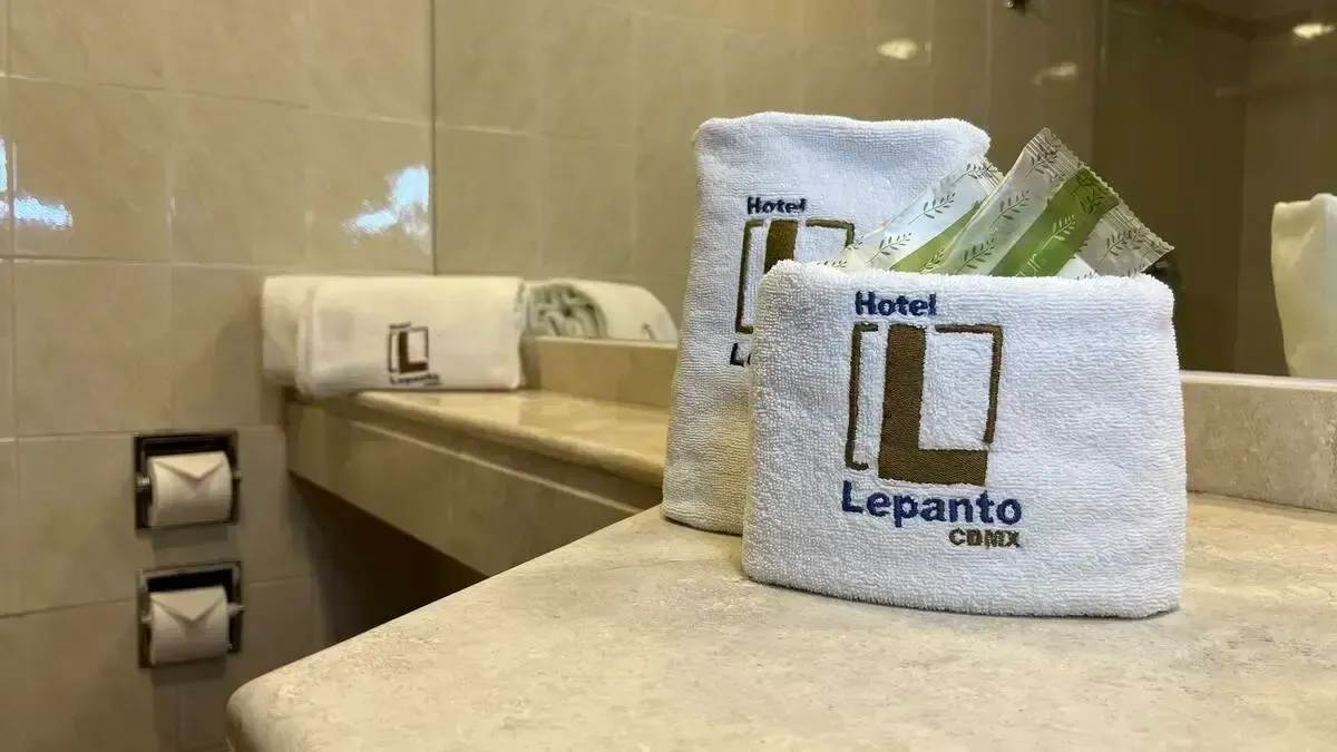 A bathroom with a sink , mirror , and towels on the counter.