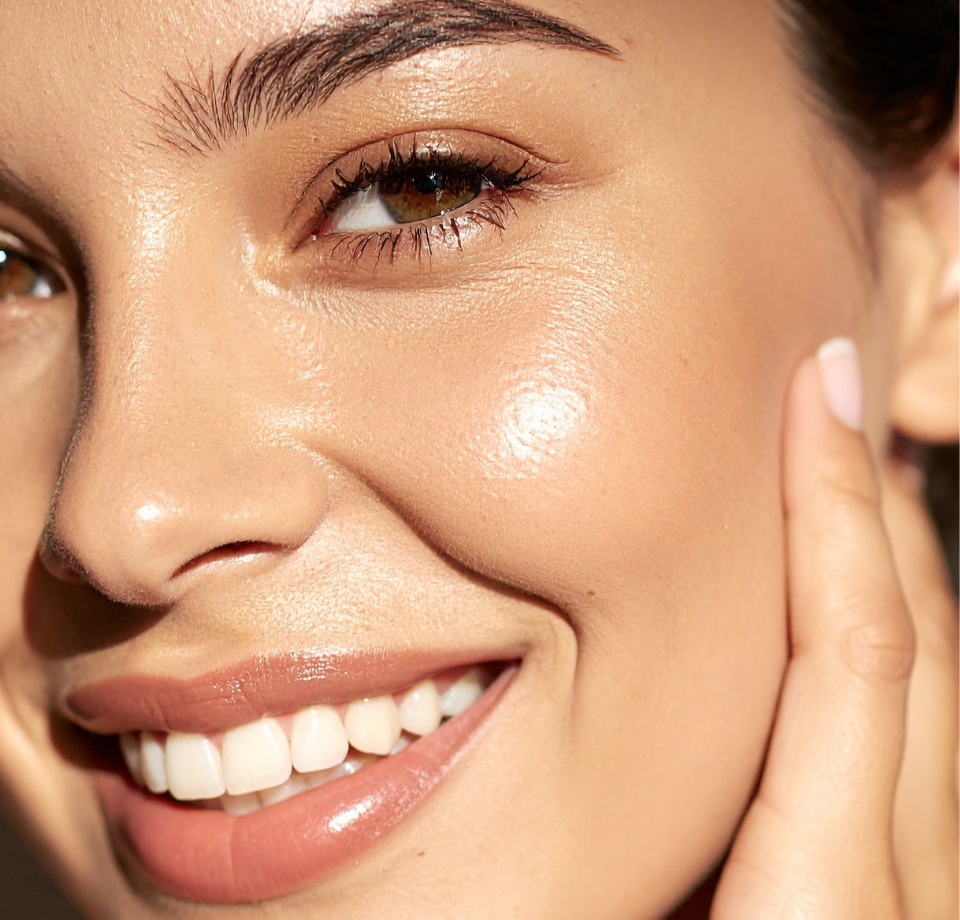 Donna con capelli corti e scuri e pelle luminosa, occhi chiusi, mano vicino al viso.