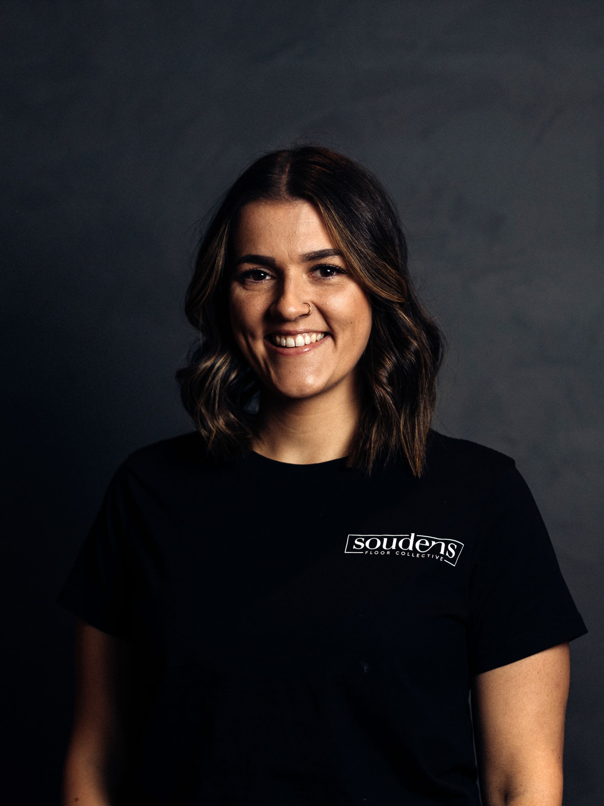 A woman is wearing a black t-shirt and smiling.