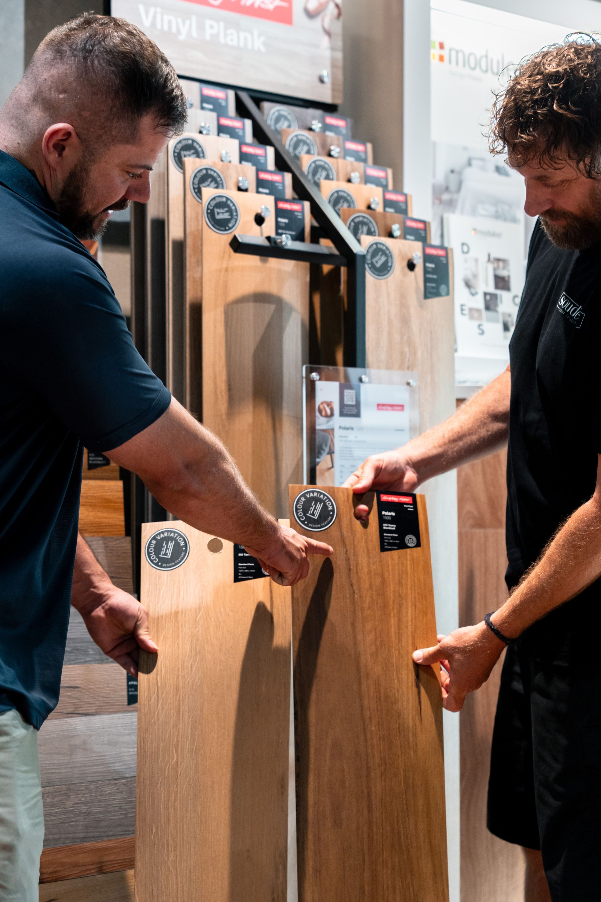 Two men are looking at a wooden floor in a store.