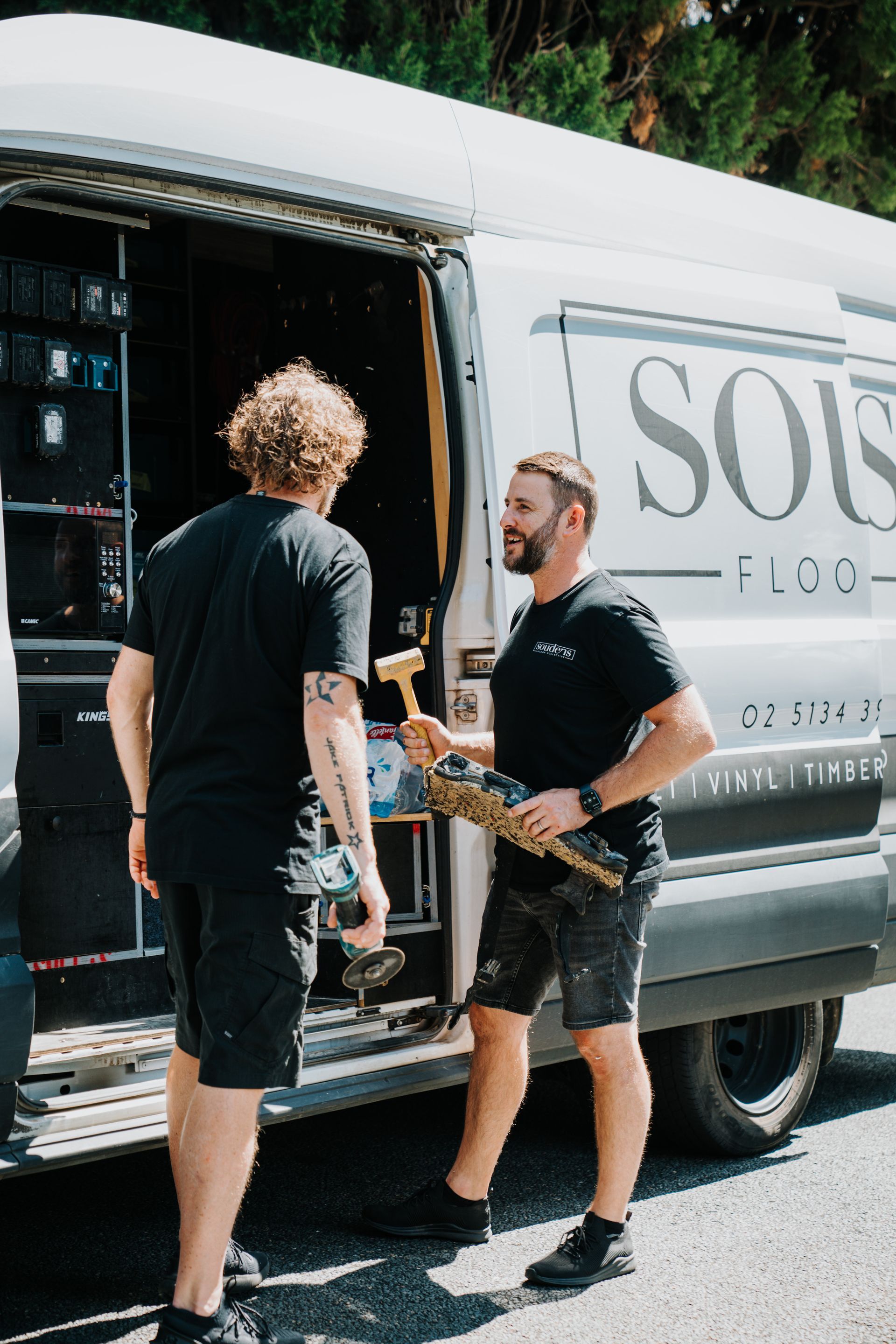 Two men are standing next to a white van.
