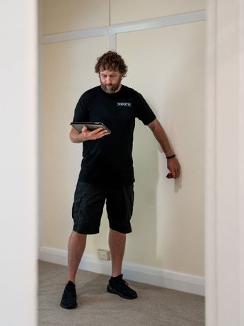 A man is standing in a room holding a tablet.