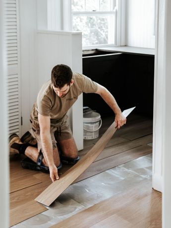 A man is installing a wooden floor in a room.