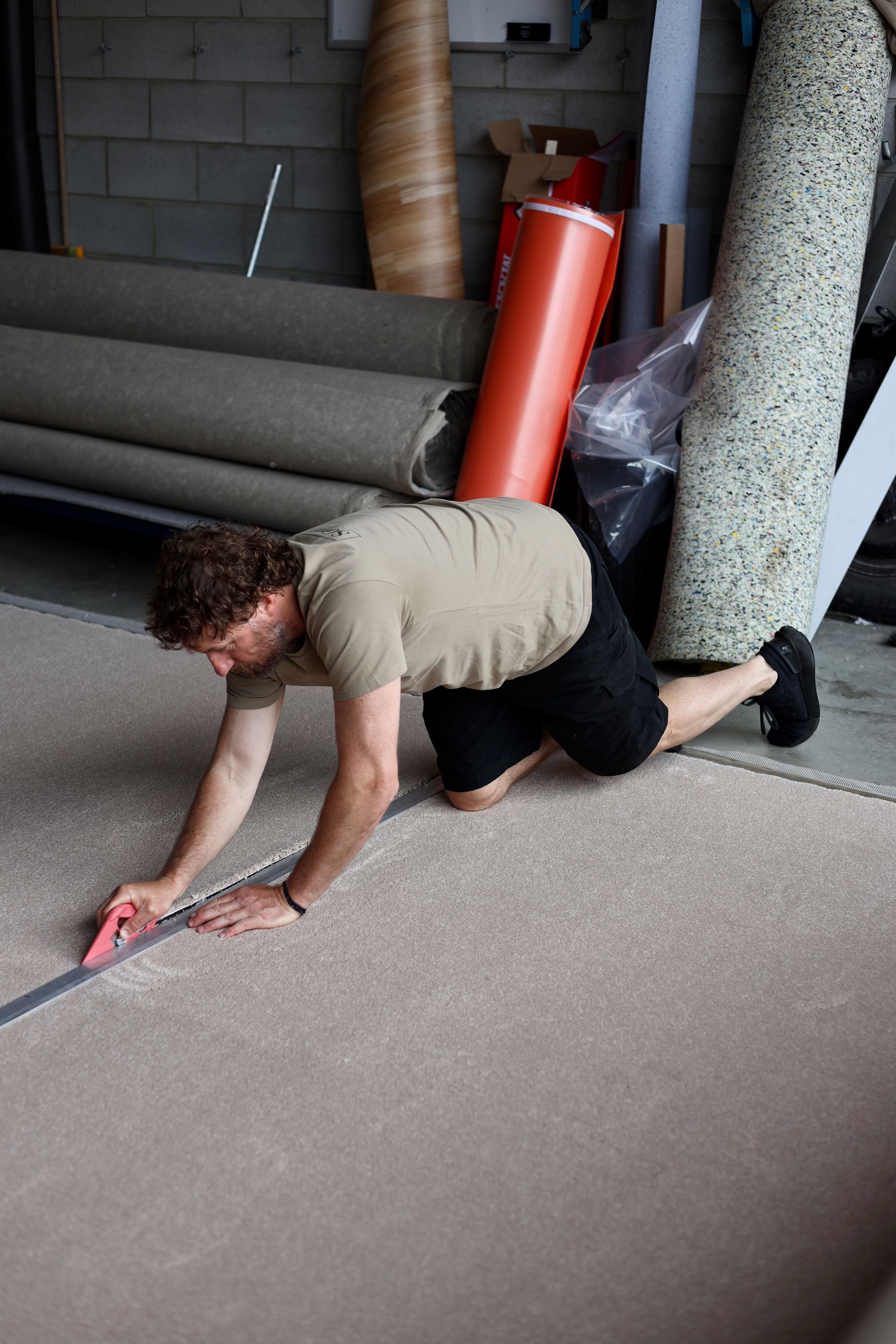 A man is measuring a carpet with a tape measure.