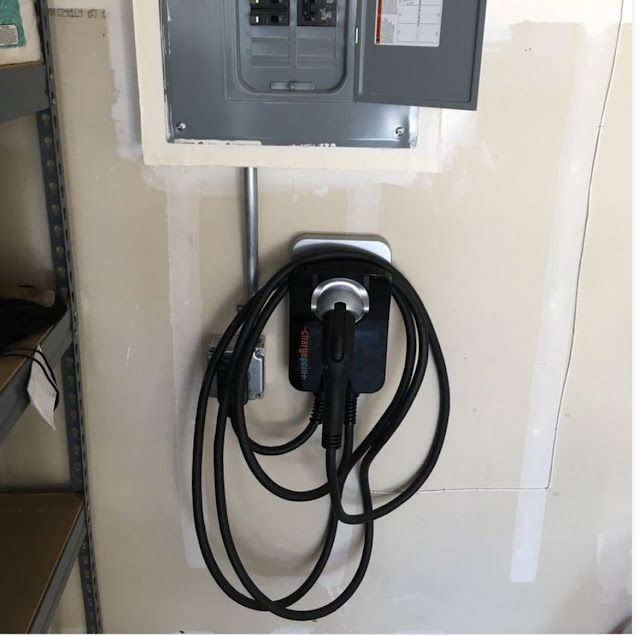 A black cord is attached to a electrical box on a wall