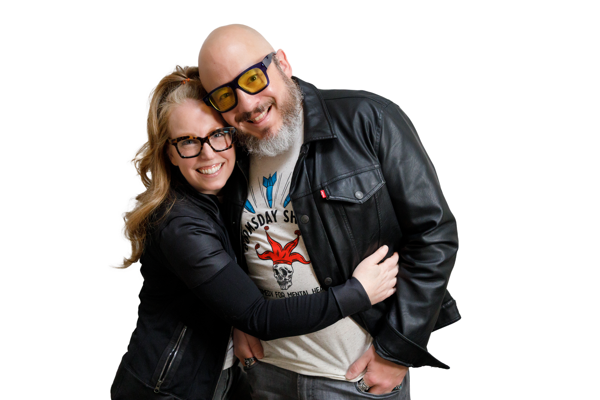 Woman in glasses hugs a man in yellow-tinted glasses and leather jacket; they smile, pose together.