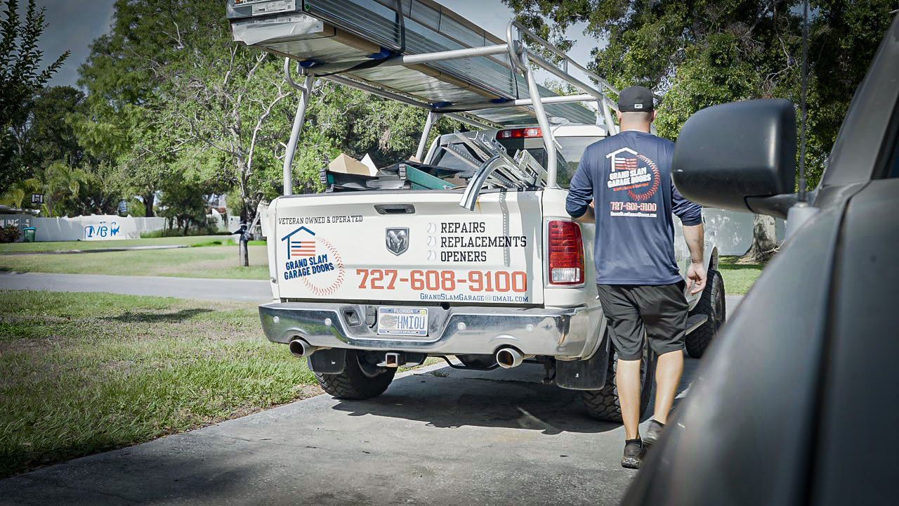 A person walks toward a white truck with tools on top. The truck has a company logo on the back.