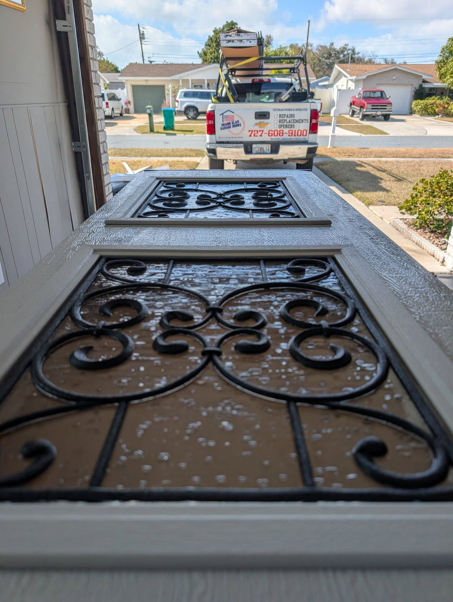 Two decorative doors with black ironwork, sitting in front of a white truck. Two decorative doors with black ironwork, sitting in front of a white truck.