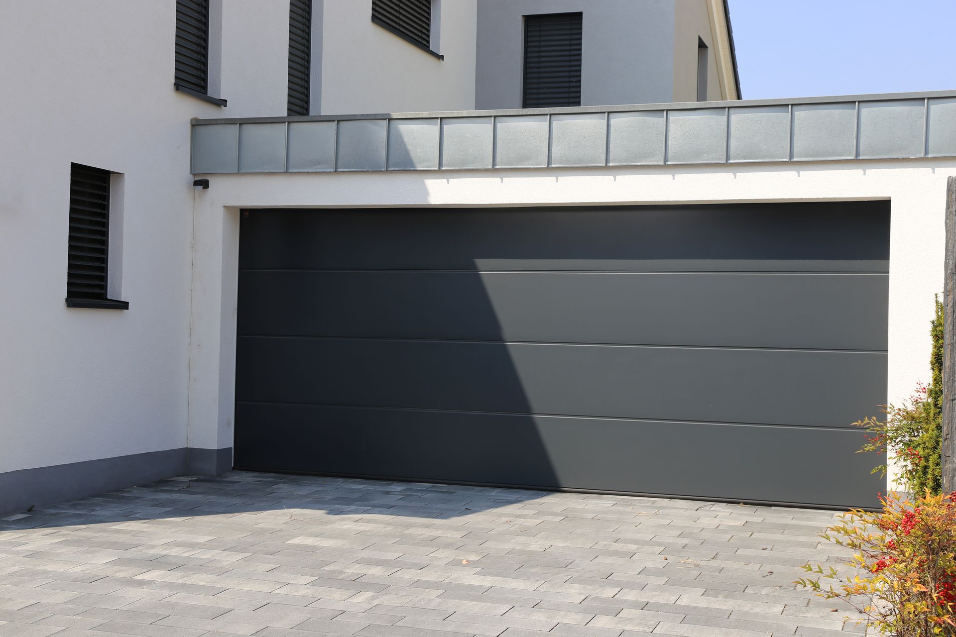 Gray garage door on a white building, brick driveway.