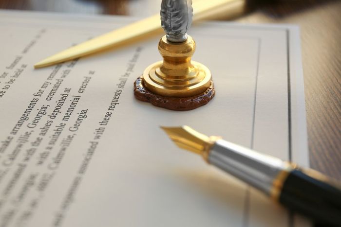 A fountain pen is sitting on top of a piece of paper next to a wax seal