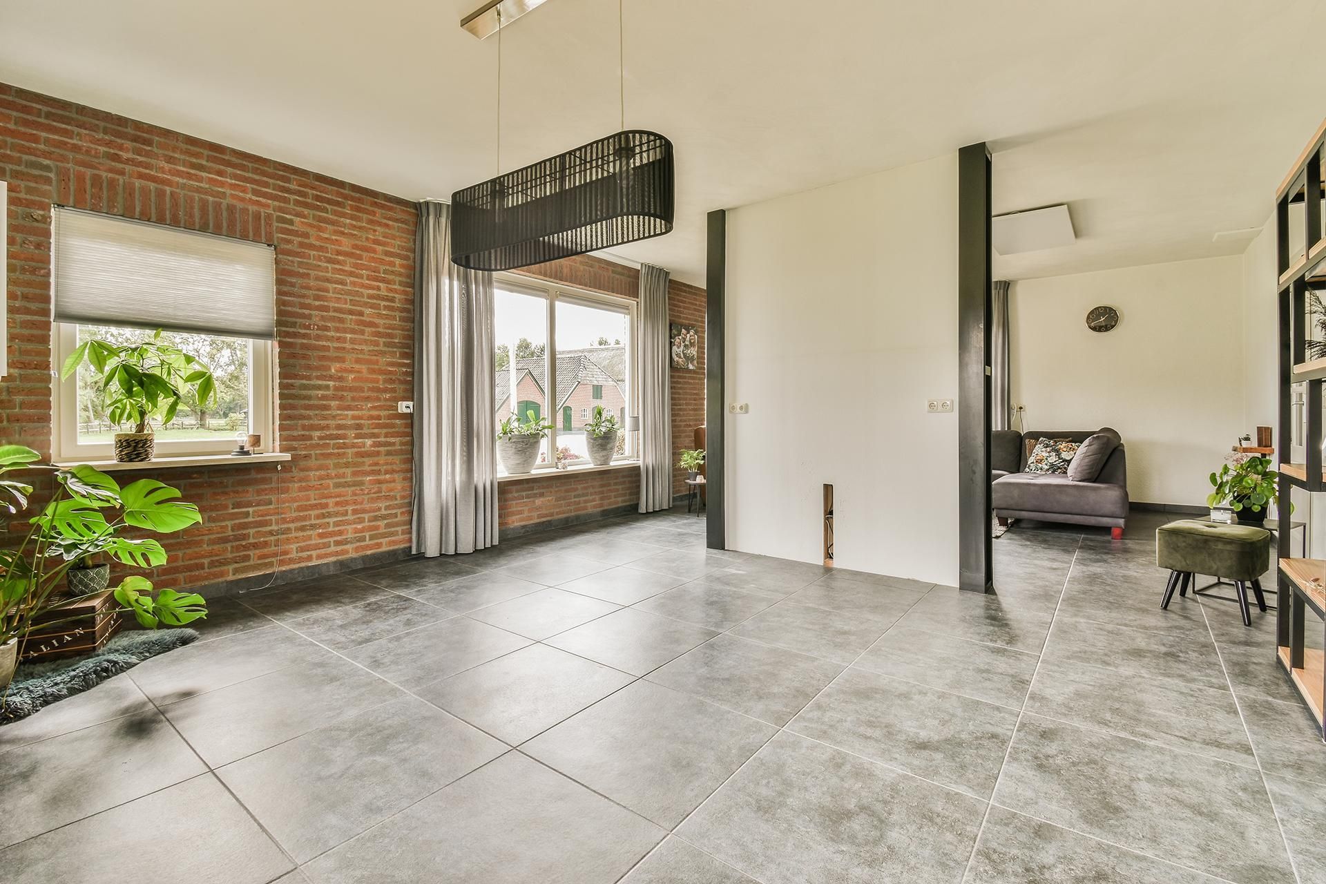 a living room with a brick wall and a gray tile floor .