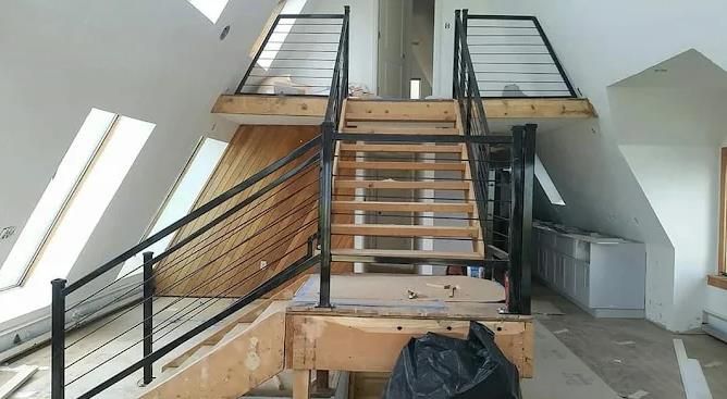 A wooden staircase with a metal railing in a room