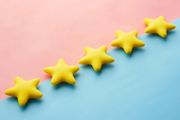 Five yellow star-shaped objects arranged diagonally across a background divided between soft pink and light blue.