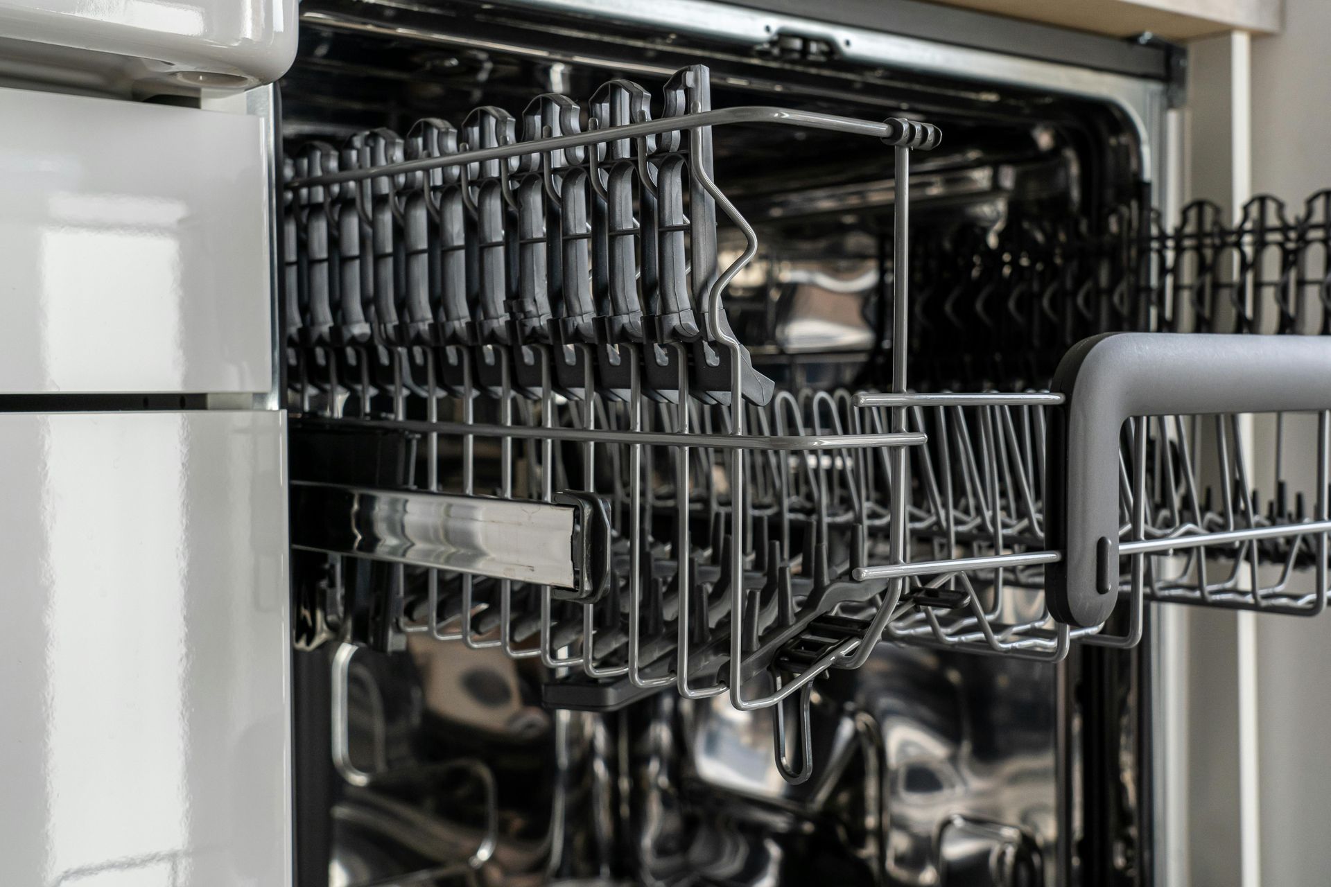 Open dishwasher interior with black racks.