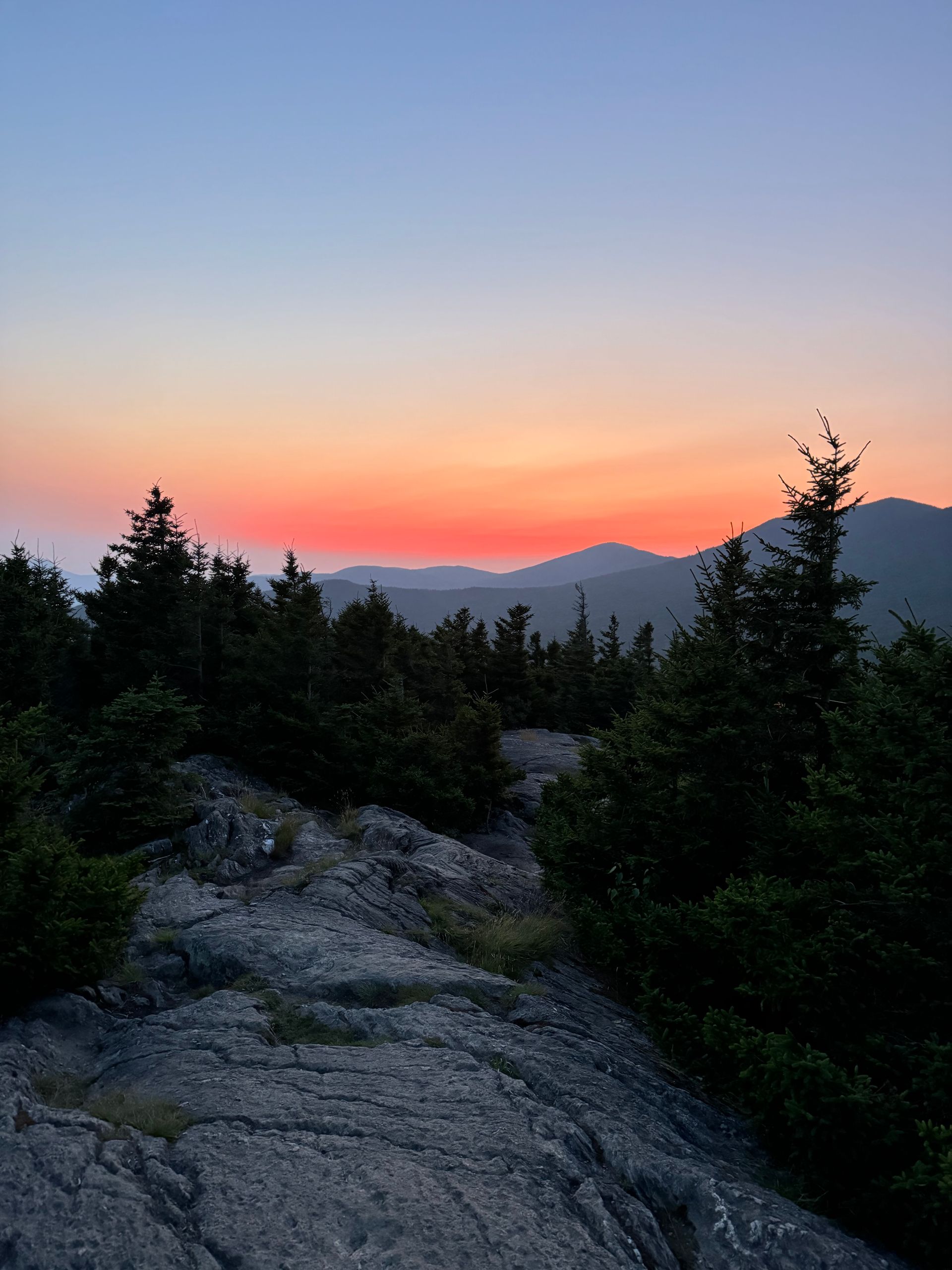 Landscape photo of a sunset or sunrise, with layers of wilderness extending to the horizon