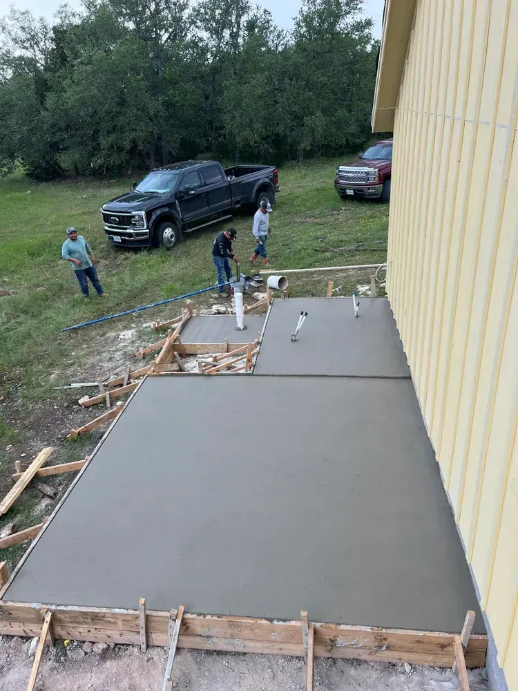 A concrete floor is being poured in front of a house.