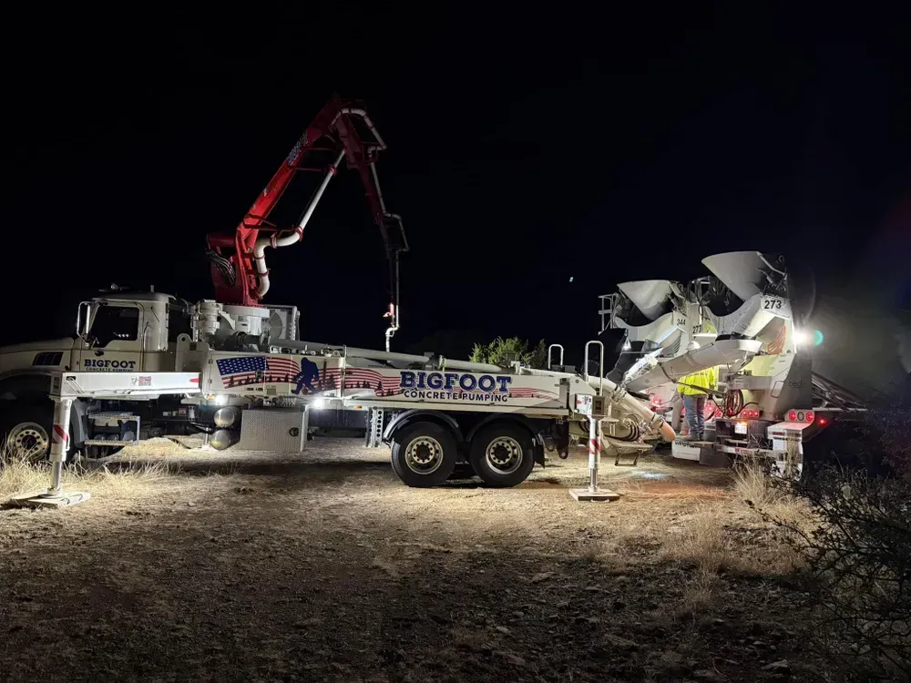 A concrete pump truck is pumping concrete at night.