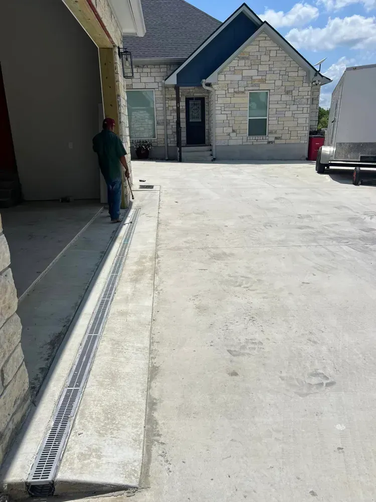 A man is standing next to a garage door in front of a house.